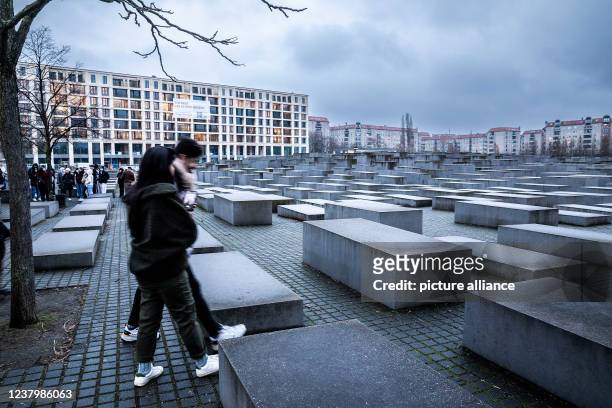 January 2022, Berlin: People walk through the field of stelae of the Memorial to the Murdered Jews of Europe, also called the Holocaust Memorial....