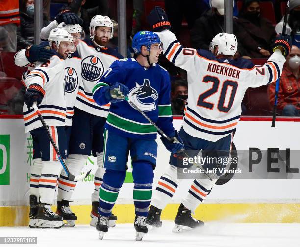 Brad Hunt of the Vancouver Canucks looks on dejected as Ryan McLeod of the Edmonton Oilers is congratulated by teammates Kris Russell, Brendan...