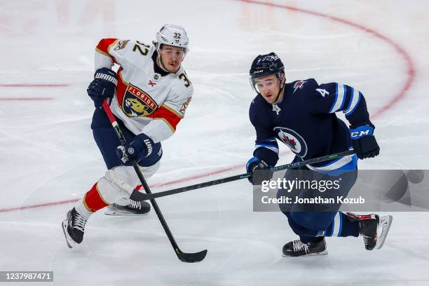 Lucas Carlsson of the Florida Panthers and Neal Pionk of the Winnipeg Jets keep an eye on the play during third period action at the Canada Life...