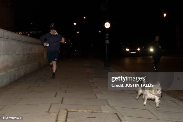 Britain's Prime Minister Boris Johnson jogs with his dog Dilyn in Westminster in London on Janurary 26, 2022. - The threat to Johnson's position...