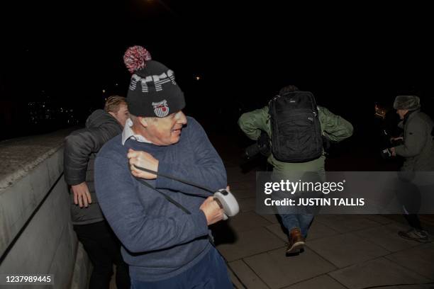 Photographer jumps over the lead of Dilyn, British Prime Minister Boris Johnson's dog, during the premier's jog in Westminster in London on Janurary...