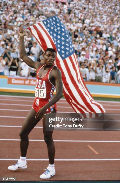 Carl Lewis of the United States carries the stars and stripes flag of the United States of America and celebrates winning the Men's 100 metres sprint...