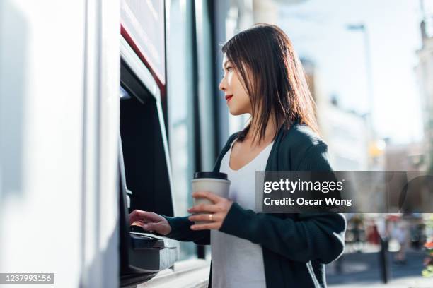 young woman withdrawing cash money at the atm - atm stock pictures, royalty-free photos & images