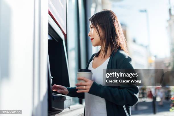 young woman withdrawing cash money at the atm - asian credit card imagens e fotografias de stock
