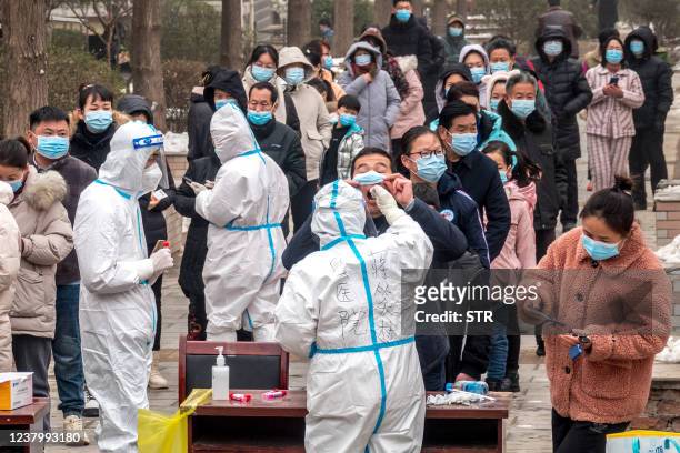 Residents queue to undergo nucleic acid tests for the Covid-19 coronavirus in Anyang in China's central Henan province on January 26, 2022. - China...