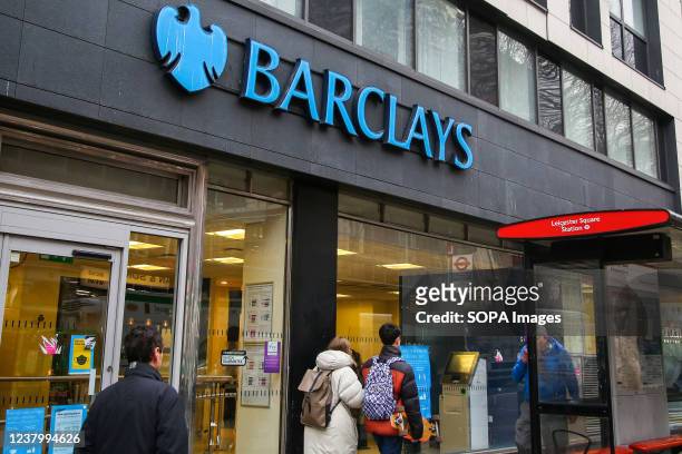 People walk past a branch of Barclays Bank.