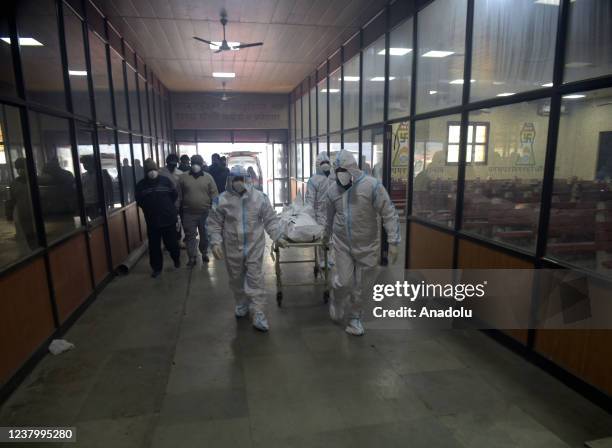 Family members and health workers carry the body of a person who has lost their life from coronavirus infection for cremation at Nigambodh Ghat...