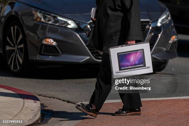 Pedestrian carries a box containing an Apple MacBook Pro computer in front of a store in Walnut Creek, California, U.S., on Tuesday, Jan. 25, 2022....