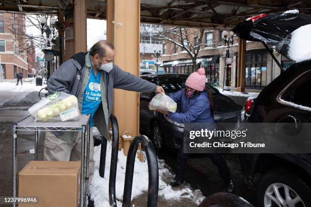 Louie Herrera, a la izquierda, voluntaria de Lakeview Pantry, ayuda a Maria Criollo a cargar artÃ­culos de supermercado en su automÃ³vil afuera de la...