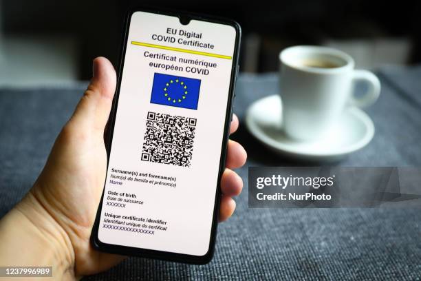 Digital COVID Certificate is displayed on a mobile phone screen photographed with a cup of coffee in the background for illustration photo during the...