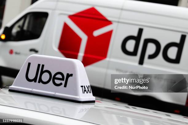 Uber sign on a car roof and DPD logo on a delivery truck are seen on the street in Krakow, Poland on January 26, 2022.