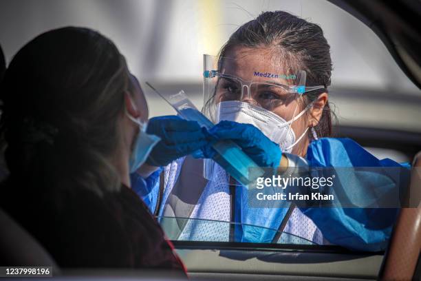 Los Angeles, CA A healthcare worker Desirae Velasquez administers a COVID19 test to Maria Lemus at a testing facility established by Total Testing...