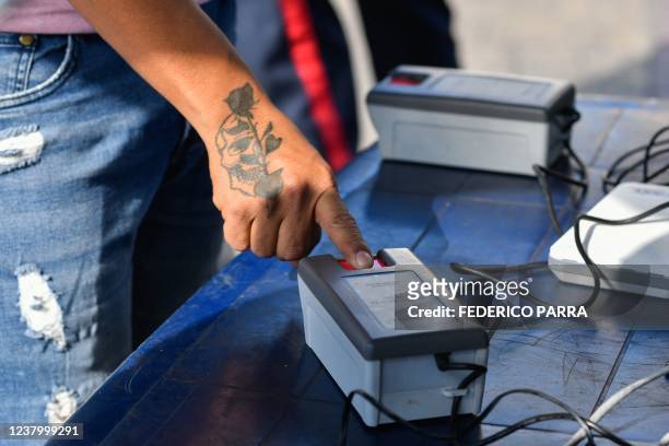 Man puts his finger on a fingerprint scanner to sign a petition in favor of holding a referendum to remove Venezuelan President Nicolas Maduro, at a...
