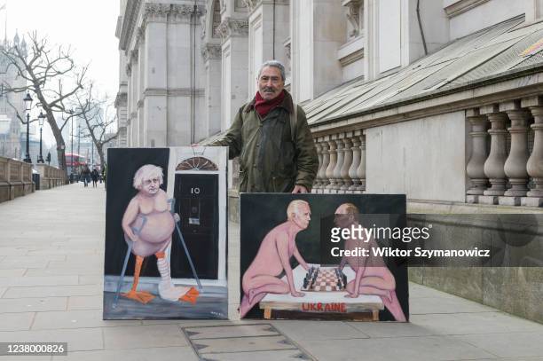 Satirical artist Kaya Mar stands with two paintings outside Downing Street, one depicting British Prime Minister Boris Johnson as a 'lame duck' in...