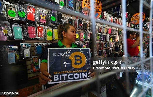 Vendor hods a sign reading "Bitcoin accepted" at a store in San Salvador, on January 26, 2022. - The International Monetary Fund urged El Salvador to...