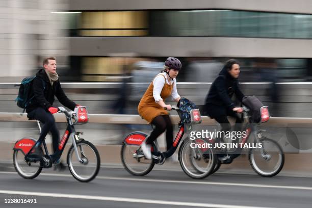 Commuters ride bicycles in central London on January 27, 2022. - Commuters in England went back to work as coronavirus restrictions imposed to tackle...
