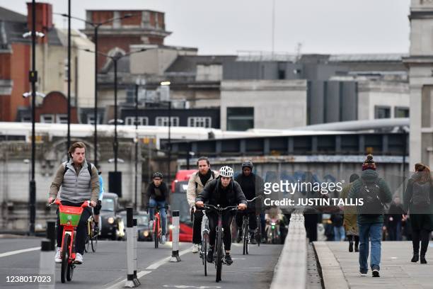 Commuters ride bicycles in central London on January 27, 2022. - Commuters in England went back to work as coronavirus restrictions imposed to tackle...