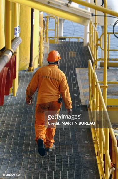Un employé d'une station offshore marche sur l'une des passerelle d'une plate-forme, le 14 octobre 2003 au large des côtes angolaises. A worker walks...