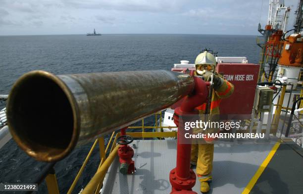 Un homme est aux commandes d'une lance à incendie au pied de l'hélideck d'une plate-forme pétrolière, le 16 octobre 2003 au large des côtes...