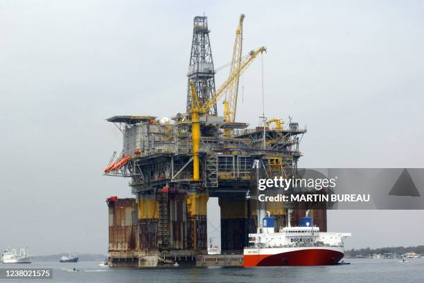 Une plateforme pétrolière est acheminée par bateau, le 14 octobre 2003, dans la baie de Luanda. AFP PHOTO MARTIN BUREAU