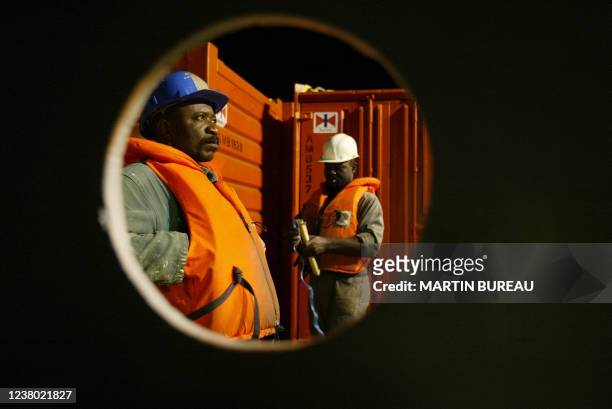 Des hommes patientent sur le pont d'un navire affrêté à une plate-forme pétrolière de Total Fina Elf, le 16 octobre 2003 au large des côtes...