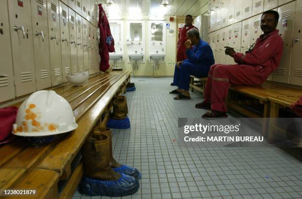 Des ouvriers d'une plate-forme pétrolière se détendent dans les vestiaires, le 15 octobre 2003 au large des côtes angolaises. Workers rest in the...