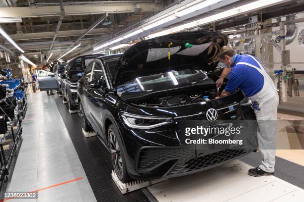 An employee checks a Volkswagen AG ID.5 electric sports utility vehicle in the light tunnel of the assembly line during a media tour of the...