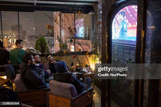 Iranian youths watch the telecast of the 2022 World Cup Asian Zone qualifier soccer match between Iran and Iraq, at a cafe in downtown Tehran on...