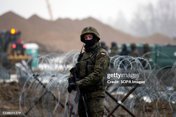 Armed border guards are seen guarding the border line with Belarus. Poland has started building a $394 million wall on its eastern border intended to...