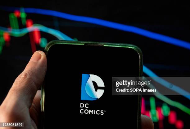 In this photo illustration the American motion picture label based at the Warner Bros, DC Comics, logo seen displayed on a smartphone with an...