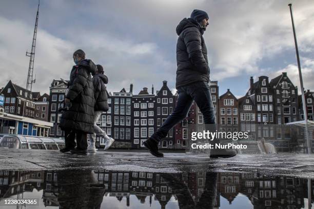 People walk in front of the famous reclining houses of Amsterdam with reflection created from the rain. Daily life during the lockdown at the fourth...