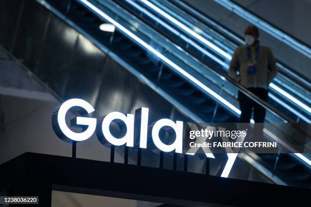 Man rides an escalator next to a booth of Galaxy mobile phones by Samsung, a main sponsor of the International Olympic Committee, at the Main Press...