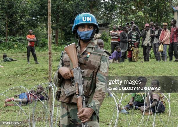 Peacekeeper holds his weapon during a patrol around the new base set up in Rugari, 50 km from the city of Goma, as the population watches the...