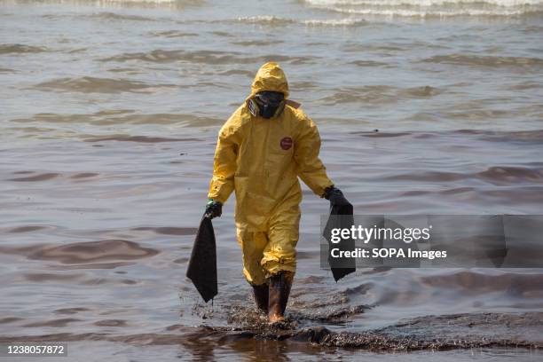 Navy sailor wearing a Personal Protective Equipment suit seen cleaning a crude oil spill on a beach. Rayong provincial officials rushed to clean up...