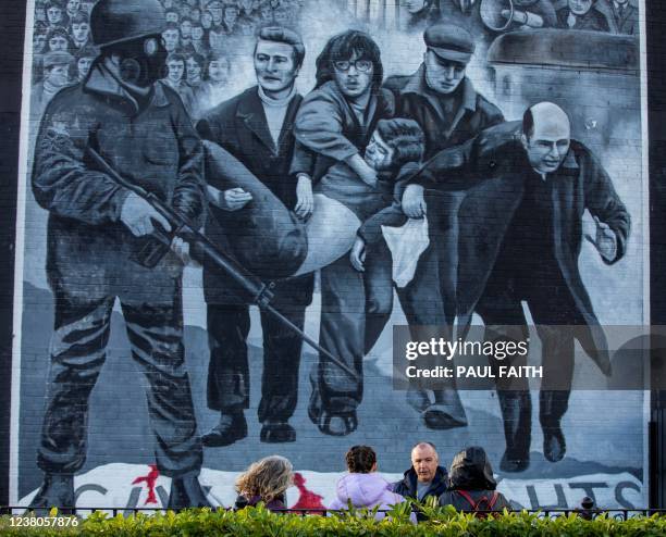 People stand beneath a mural depicting the late Bishop Edward Daly waving a white handkerchief as Jackie Duddy is carried away during the 1972 Bloody...