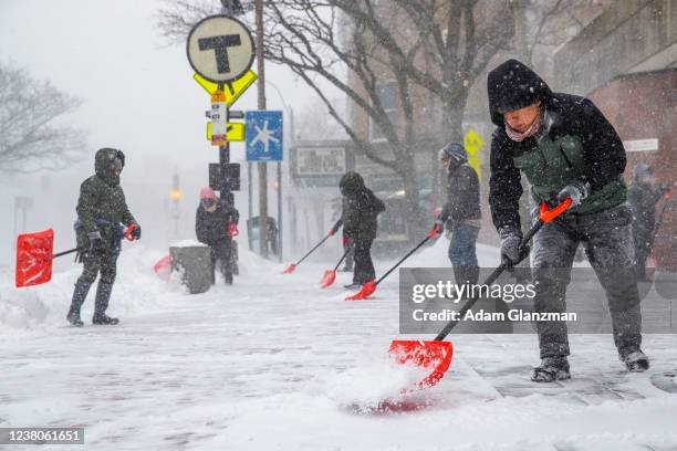 People shovel outside of the Davis Square MBTA station during a snowstorm on January 29, 2022 in Somerville, Massachusetts. A powerful noreaster...