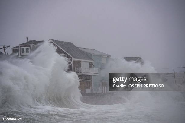 Waves crash over oceanfront homes during a noreaster in Scituate, Massachusetts on January 29, 2022. - Blinding snow whipped up by near-hurricane...