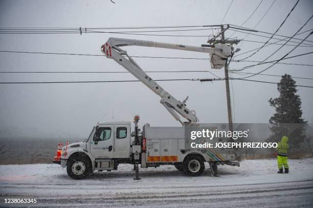 Electrical utility crew works on a power line during a noreaster in Scituate, Massachusetts, on January 29, 2022. - Blinding snow whipped up by...