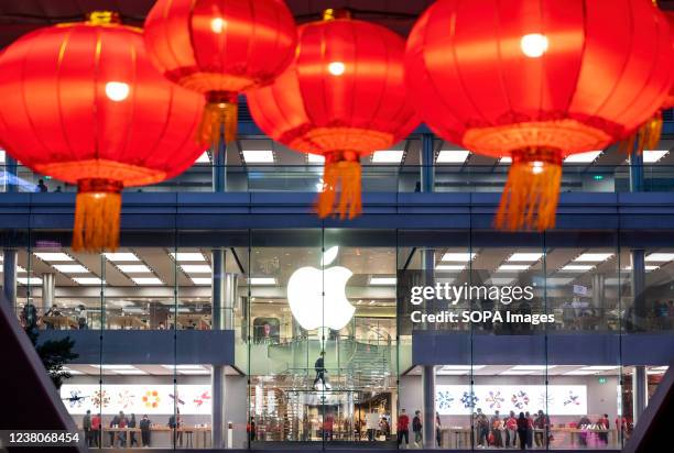 Red lanterns for Chinese Lunar New Year hang from a pedestrian bridge as the American multinational technology company Apple store is seen in the...