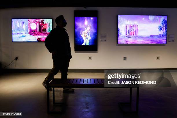 Visitor walks among artwork on display during the opening weekend of the Seattle NFT Museum in Seattle, Washington on January 29, 2022. - Using the...