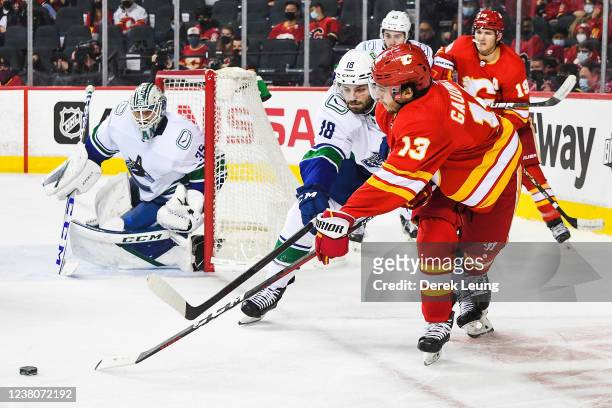 Johnny Gaudreau of the Calgary Flames fights for the puck against Jason Dickinson of the Vancouver Canucks during an NHL game at Scotiabank...