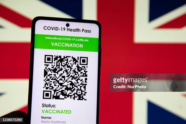 Green Pass vaccination certificate with the flag of the United Kingdom UK - Great Britain in the background displayed on a screen - Photo...