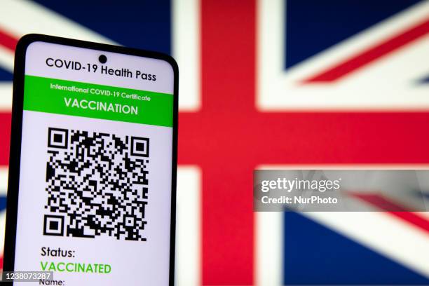 Green Pass vaccination certificate with the flag of the United Kingdom UK - Great Britain in the background displayed on a screen - Photo...