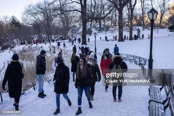 People walk on a snow-covered path in Central Park after a powerful winter snow storm on January 30, 2022 in New York City. - Blinding snow whipped...