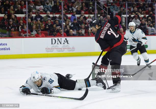 Radim Simek of the San Jose Sharks falls to the ice as Nino Niederreiter of the Carolina Hurricanes looks to gain possession of a loose puck during...