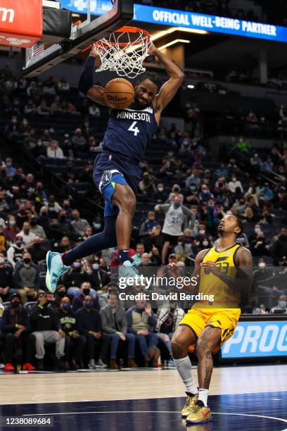 Jaylen Nowell of the Minnesota Timberwolves dunks the ball on an alley-oop while Elijah Hughes of the Utah Jazz reacts in the second quarter of the...