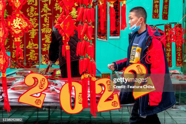 Man walks by decorative items on sale in an open-air market in a shopping spree for the upcoming Spring Festival in Huaxian county in central Chinas...