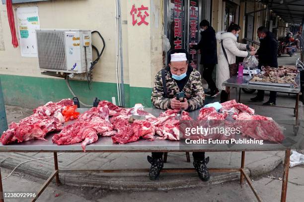 Butcher waits for customers at an open-air market in a shopping spree for the upcoming Spring Festival in Huaxian county in central Chinas Henan...