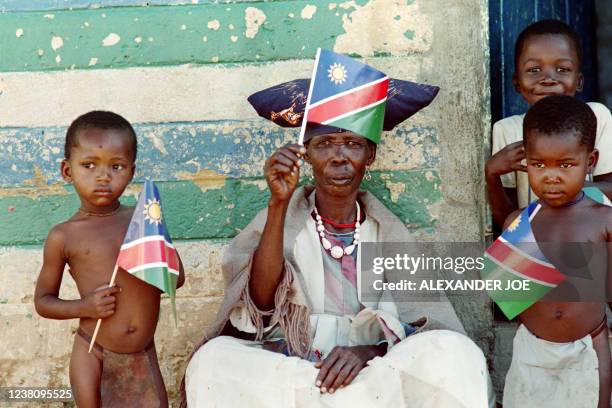 Herero woman in traditional attire and children , wave Namibia's new flag ahead of the country's independence from South Africa after 23 years of...