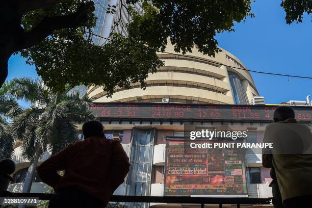 Pedestrians watch a digital screen relaying the budget speech by Indian Finance Minister Nirmala Sitharaman on the facade of the Bombay Stock...